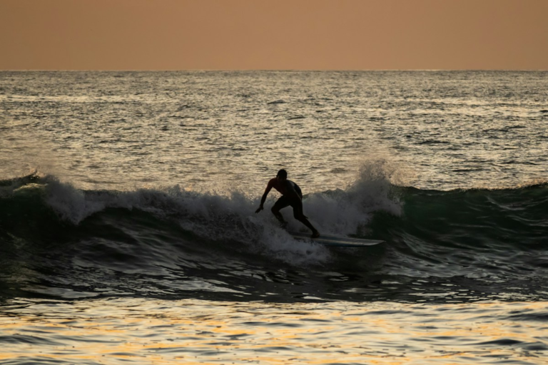 Surfer riding a wave at sunset in Nosara, Costa Rica