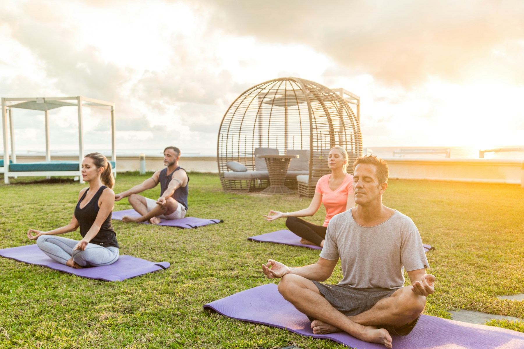 Adults enjoying an outdoor yoga class at sunrise; activity illustration