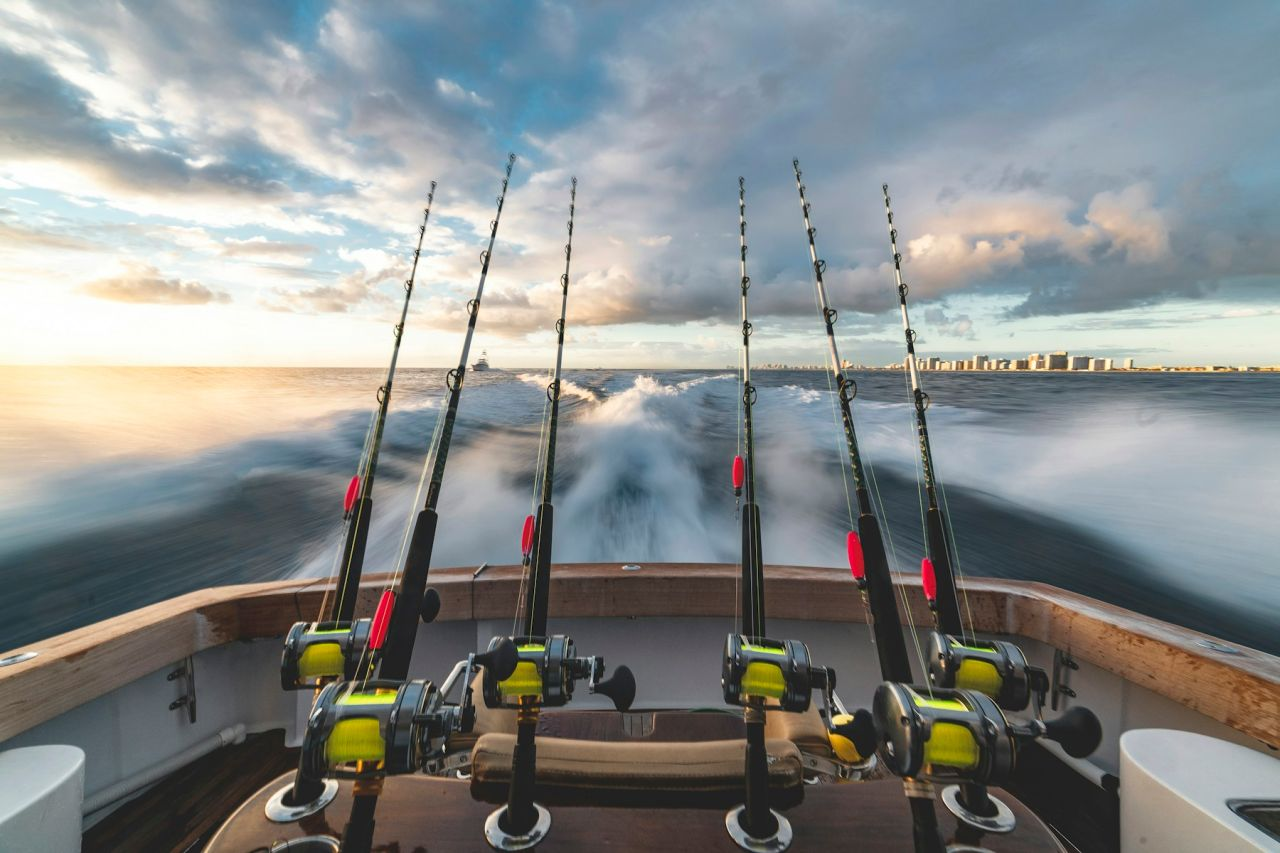 Sport fishing rods and reels above a boat wake at sunrise